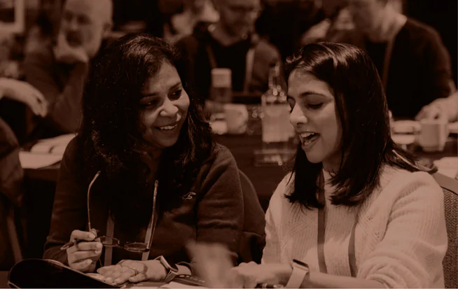 Two delegates smiling and talking at a Property Entrepreneur training table